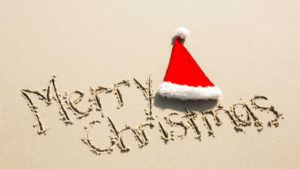 merry-christmas-written-sand-with-santa-hat