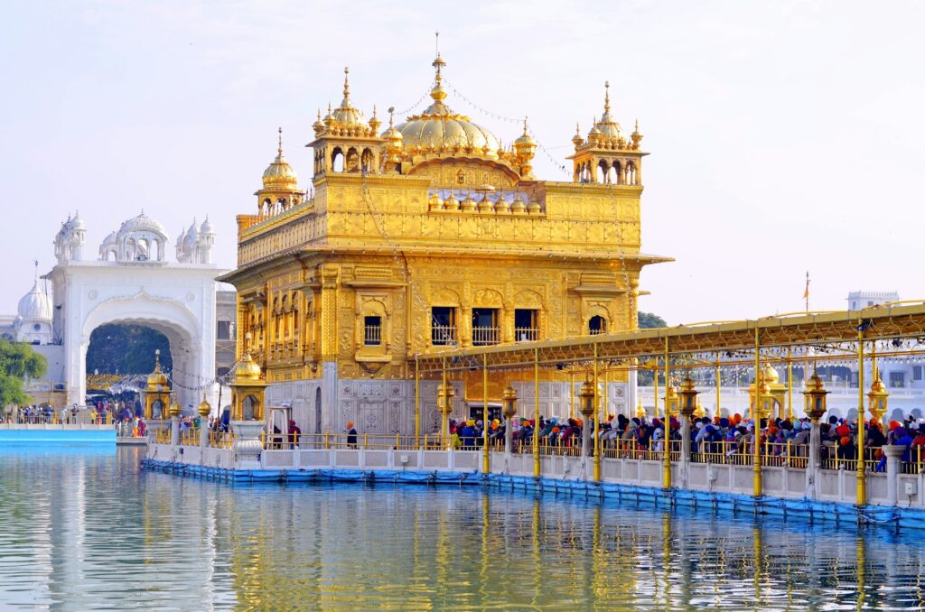 people walking near white concrete building during daytime at Golden Temple in Amritsar